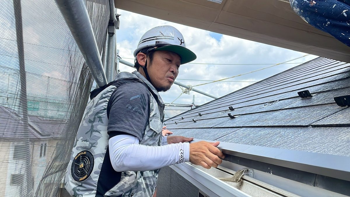 屋根の上で棟板金の浮きを点検する職人